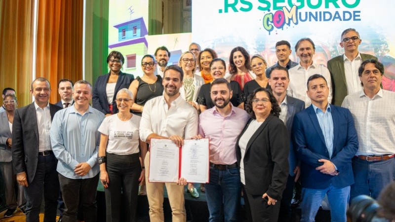 Governador Eduardo Leite segurando o Assinado contrato do programa RS Seguro COMunidade, junto com ele os profissionais dos mais segmentos de secretaria do estado (educação, cultura,saúde etc.)